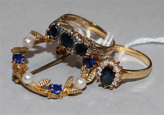 A 9ct gold, sapphire and diamond half-hoop ring, an 18ct gold, sapphire and diamond cluster ring and a yellow metal wreath brooch,